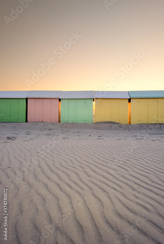 Pastel colored beach huts against sunset sky in Berck (France)