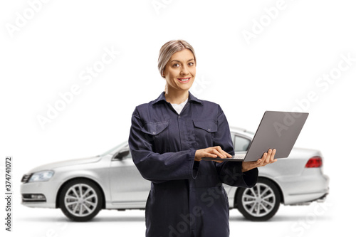 A silver car and a female auto mechanic worker in a uniform holding a laptop computer