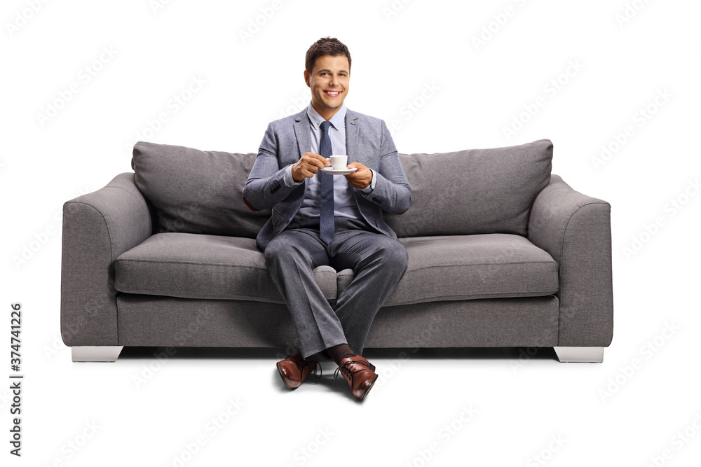 Young man sitting on a sofa with a cup of coffee Young man sitting on a sofa with a cup of coffee
