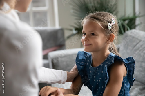Smiling little pretty kid girl enjoying trustful sincere conversation with mother or nanny  getting support or feeling secured at home. Happy small daughter making peace with mommy  children custody.