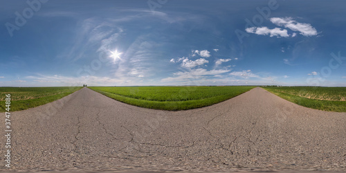 Full spherical seamless panorama 360 degrees angle view on no traffic old asphalt road among fields with clear sky and white clouds in equirectangular projection  VR AR content