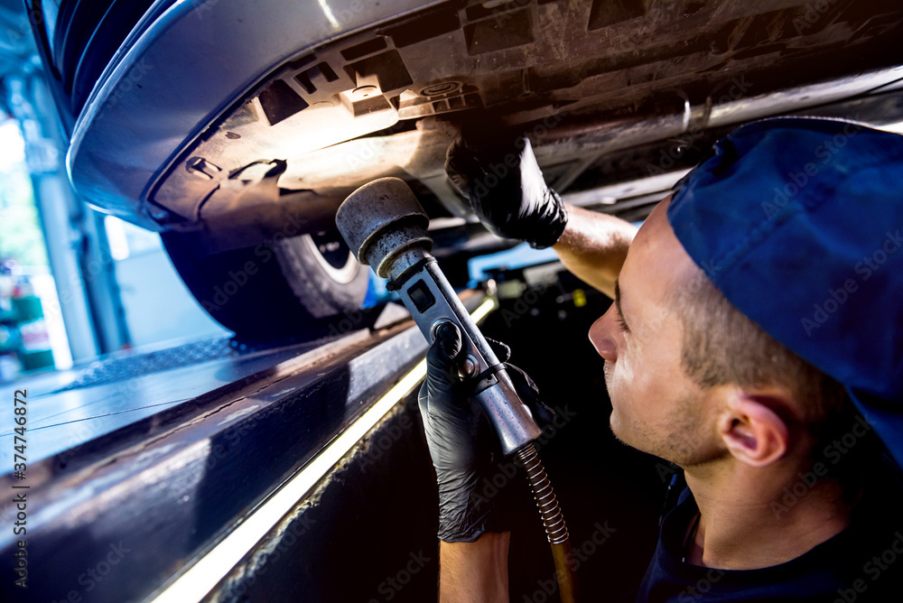 Φωτογραφία Car mechanic examining car suspension of lifted automobile at service station