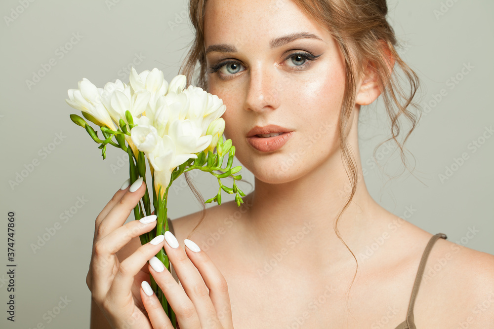 Pretty woman with natural healthy skin with freckles holding white flowers