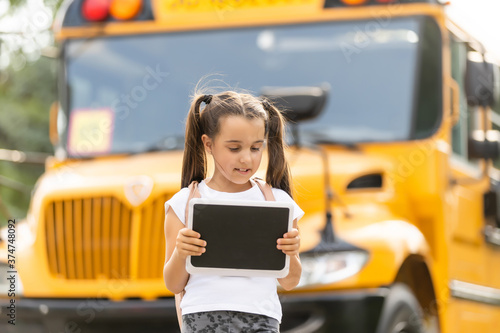 Cute girl with a backpack standing near bus going to school posing to camera pensive close-up