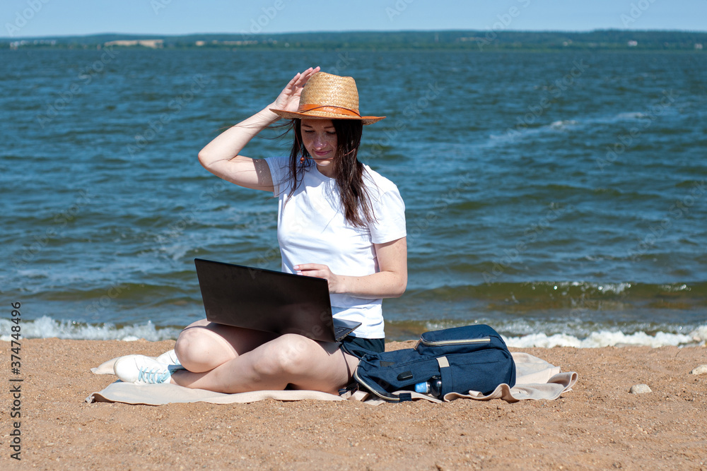 Young woman using laptop computer on sunbed on a beach. Freelance work concept, Freelancer outside