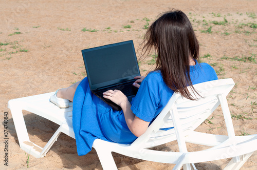 Young woman using laptop computer on a beach. Freelance work concept