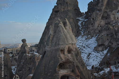 Another hilltop view of the fairy chimneys and historical caves in Cappadocia. Cappadocia from the top on a snowy winter day. Settlements beyond the fairy chimneys. The path leading up the hill. 