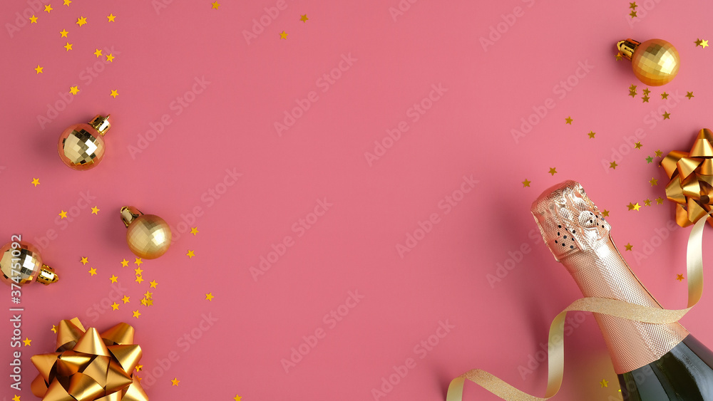 Champagne bottle with confetti stars, golden balls decorations and party streamer on pink background. Christmas party or birthday concept. Flat lay, top view.