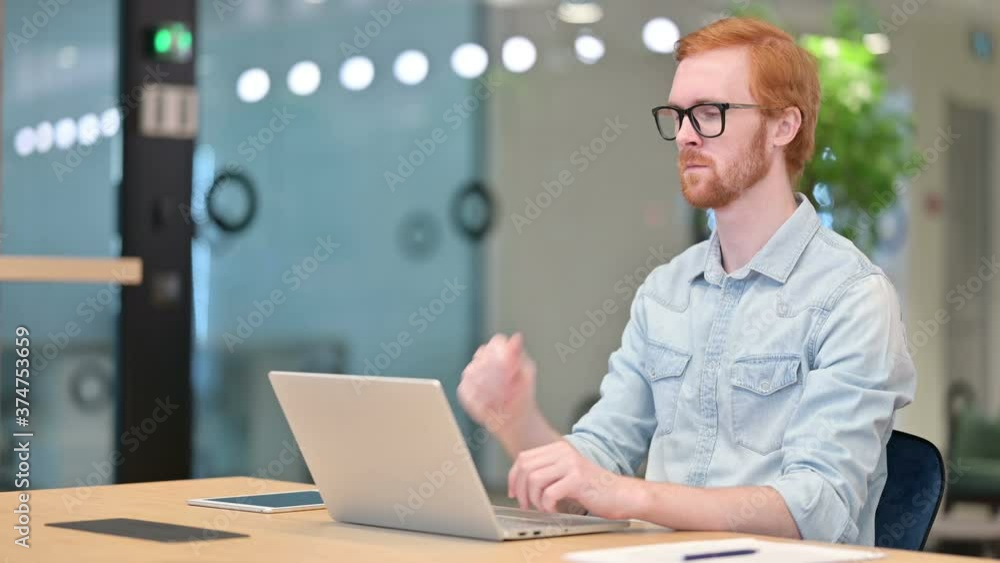 Pensive Casual Redhead Man Thinking and Working on Laptop in Office Pensive Casual Redhead Man Thinking and Working on Laptop in Office