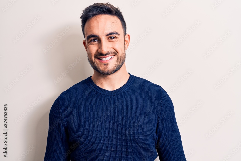 Young handsome man with beard wearing casual sweater standing over white background with a happy and cool smile on face. Lucky person. Young handsome man with beard wearing casual sweater standing over white background with a happy and cool smile on face. Lucky person.