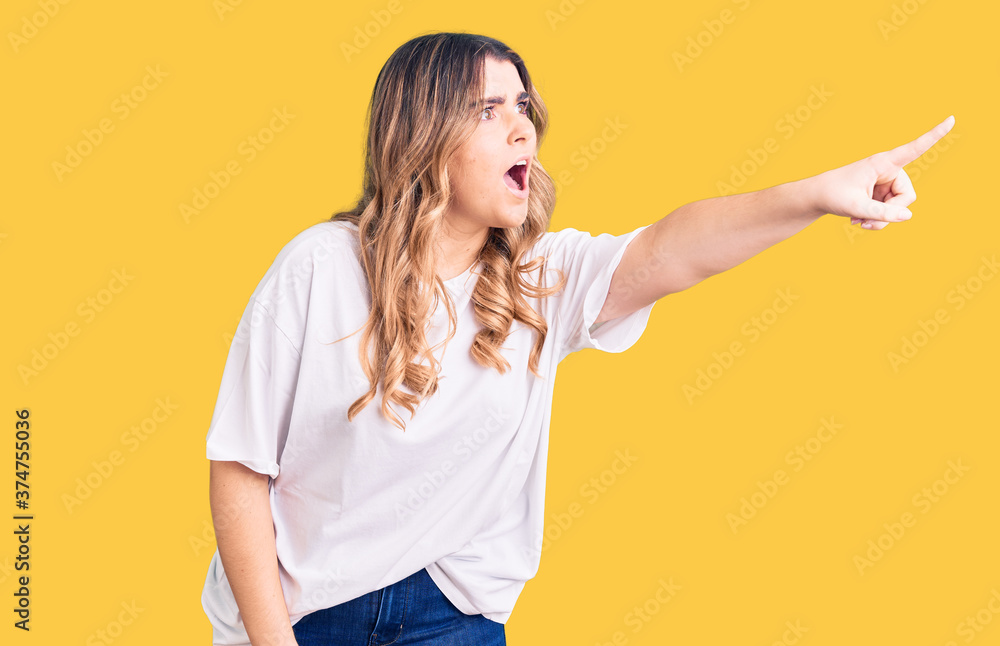Young caucasian woman wearing casual clothes pointing with finger surprised ahead, open mouth amazed expression, something on the front Young caucasian woman wearing casual clothes pointing with finger surprised ahead, open mouth amazed expression, something on the front