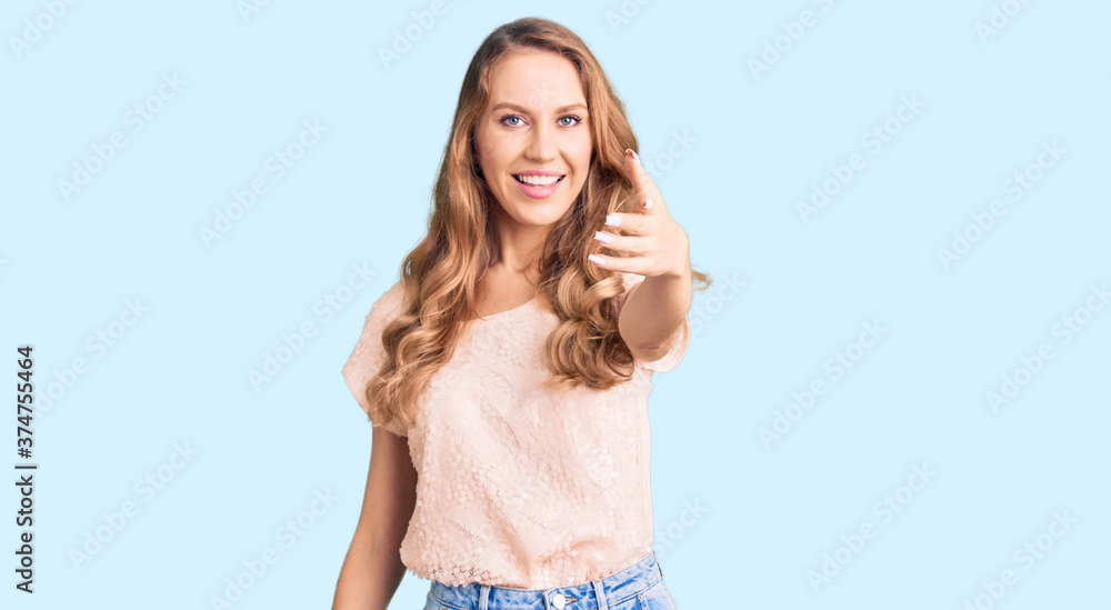 Young beautiful caucasian woman with blond hair wearing casual clothes smiling friendly offering handshake as greeting and welcoming. successful business. Young beautiful caucasian woman with blond hair wearing casual clothes smiling friendly offering handshake as greeting and welcoming. successful business.