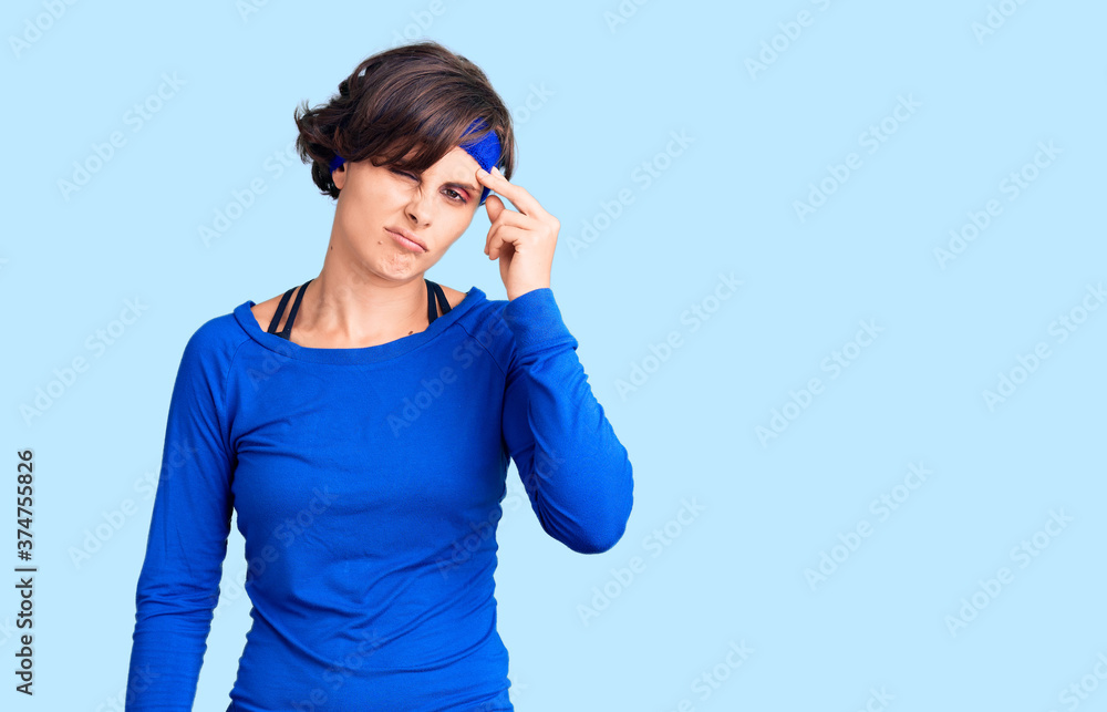 Beautiful young woman with short hair wearing training workout clothes worried and stressed about a problem with hand on forehead, nervous and anxious for crisis Beautiful young woman with short hair wearing training workout clothes worried and stressed about a problem with hand on forehead, nervous and anxious for crisis