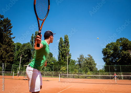 Young athletic man playing tennis on the court. © romaset