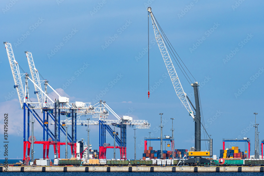 The infrastructure of the commercial port. Cranes for loading and unloading operations in the port. Loading of ships and railway cars. Transport terminal. Different types of cargo transportation.