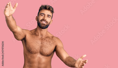 Foto Young hispanic man wearing swimwear shirtless looking at the camera smiling with open arms for hug