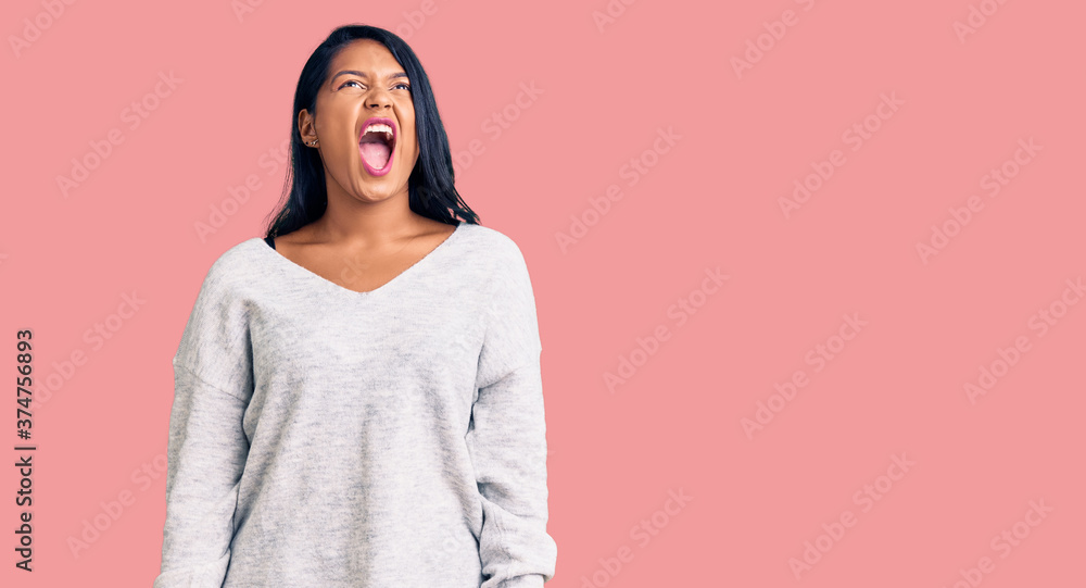 Hispanic woman with long hair wearing casual clothes angry and mad screaming frustrated and furious, shouting with anger. rage and aggressive concept.