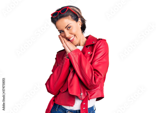 Young beautiful woman wearing red leather jacket praying with hands together asking for forgiveness smiling confident.