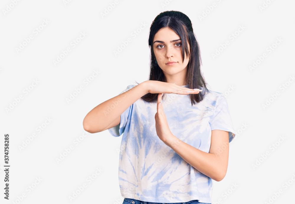Young beautiful girl wearing casual t shirt doing time out gesture with hands, frustrated and serious face Young beautiful girl wearing casual t shirt doing time out gesture with hands, frustrated and serious face