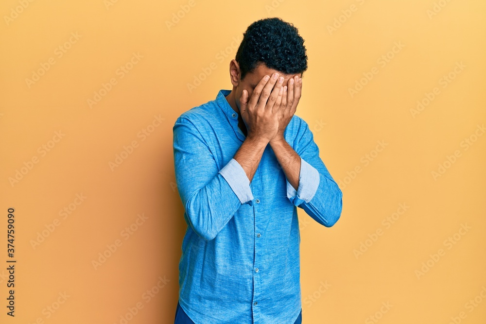 Young arab man wearing casual clothes with sad expression covering face with hands while crying. depression concept. Young arab man wearing casual clothes with sad expression covering face with hands while crying. depression concept.