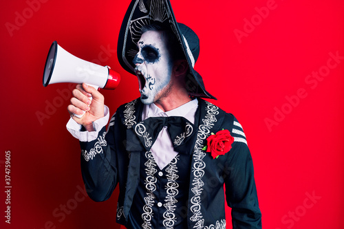 Scary man wearing day of the dead make up and costumbre from traditional ritual in Mexico shouting through megaphone