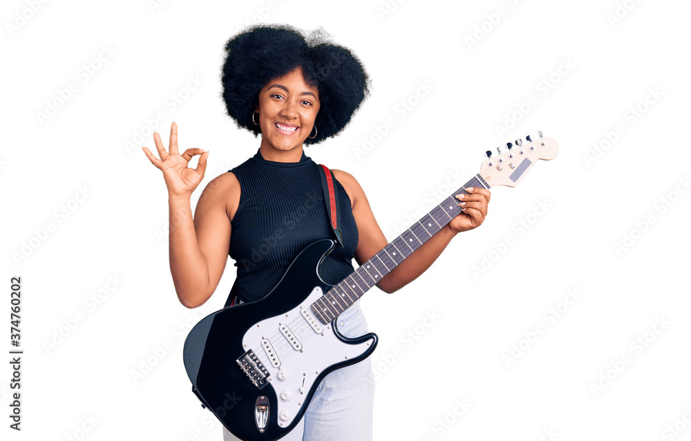 Young african american girl playing electric guitar doing ok sign with fingers, smiling friendly gesturing excellent symbol