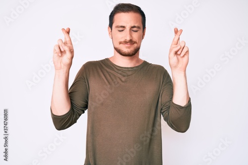 Young handsome man wearing casual clothes gesturing finger crossed smiling with hope and eyes closed. luck and superstitious concept.