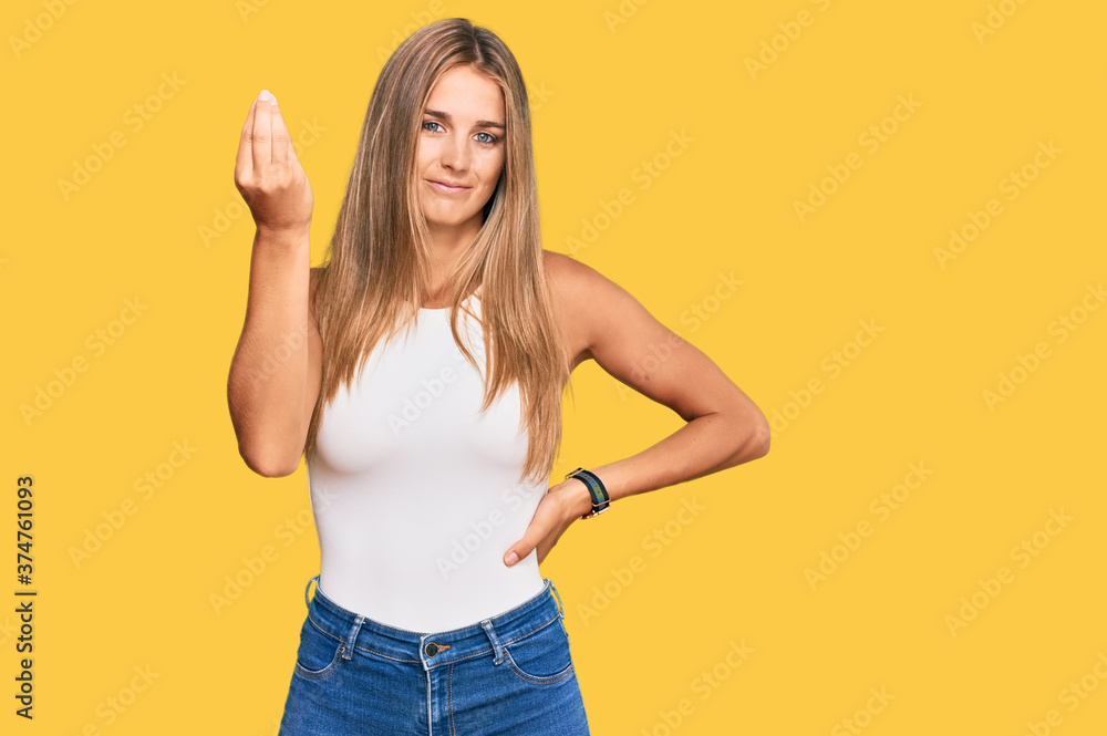 Young blonde woman wearing casual style with sleeveless shirt doing italian gesture with hand and fingers confident expression Young blonde woman wearing casual style with sleeveless shirt doing italian gesture with hand and fingers confident expression