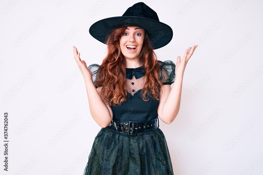 Young beautiful woman wearing witch halloween costume celebrating crazy and amazed for success with arms raised and open eyes screaming excited. winner concept