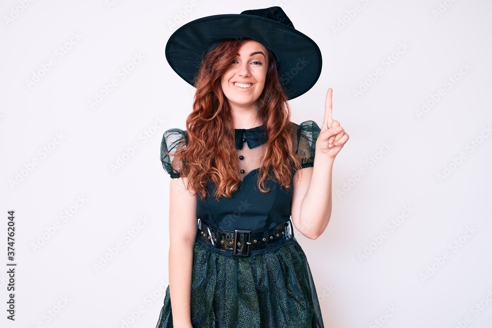 Young beautiful woman wearing witch halloween costume showing and pointing up with finger number one while smiling confident and happy. Young beautiful woman wearing witch halloween costume showing and pointing up with finger number one while smiling confident and happy.