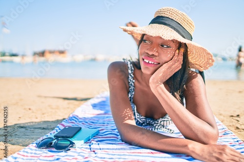 Young african american woman on vacation smiling happy laying on the towel at the beach