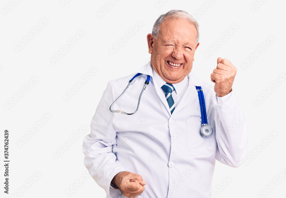 Senior handsome grey-haired man wearing doctor coat and stethoscope celebrating surprised and amazed for success with arms raised and eyes closed. winner concept. Senior handsome grey-haired man wearing doctor coat and stethoscope celebrating surprised and amazed for success with arms raised and eyes closed. winner concept.