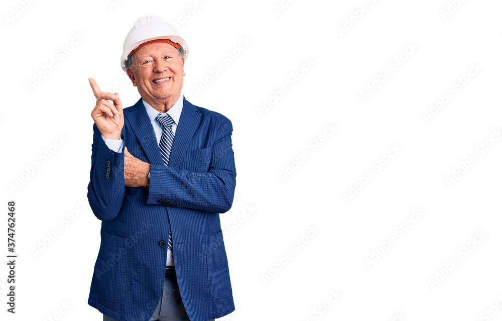 Senior handsome grey-haired man wearing suit and architect hardhat with a big smile on face, pointing with hand and finger to the side looking at the camera. Senior handsome grey-haired man wearing suit and architect hardhat with a big smile on face, pointing with hand and finger to the side looking at the camera.