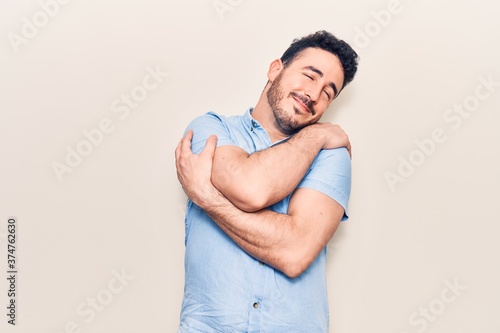 Young hispanic man wearing casual clothes hugging oneself happy and positive, smiling confident. self love and self care