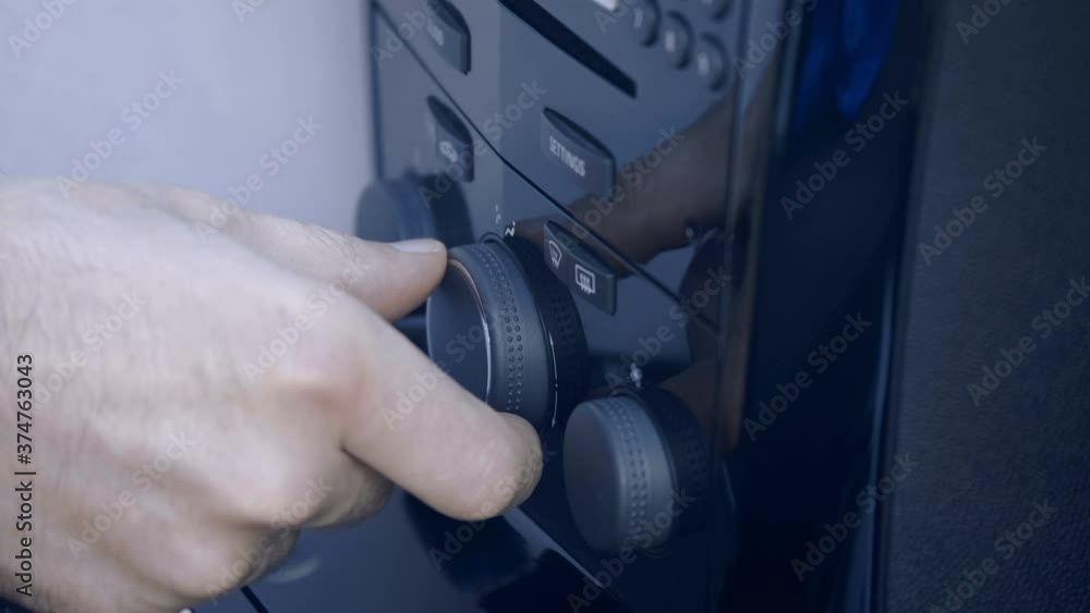 The driver's hand controls the power and direction of ventilation and air conditioning on the shiny black dashboard of the car. Closeup The driver's hand controls the power and direction of ventilation and air conditioning on the shiny black dashboard of the car. Closeup
