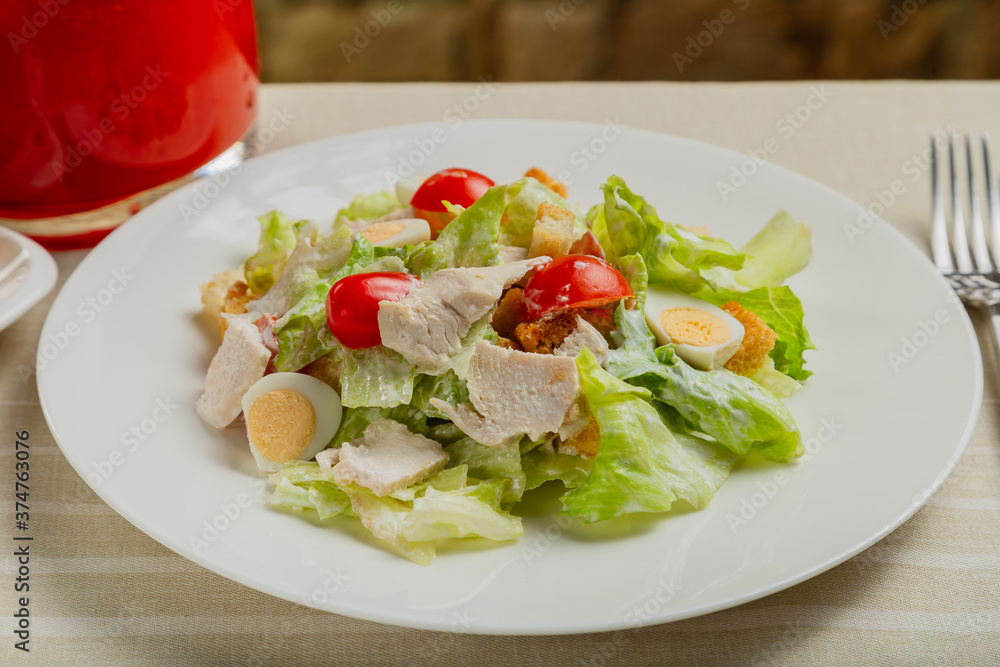 Fresh caesar salad in a white plate on the table. Fresh caesar salad in a white plate on the table.