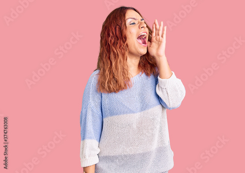 Young latin woman wearing casual clothes shouting and screaming loud to side with hand on mouth. communication concept.