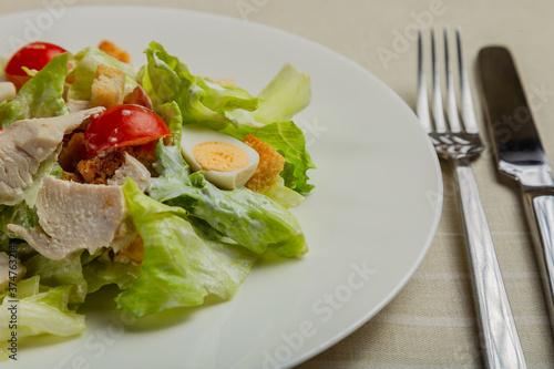 Fresh caesar salad in a white plate on the table.