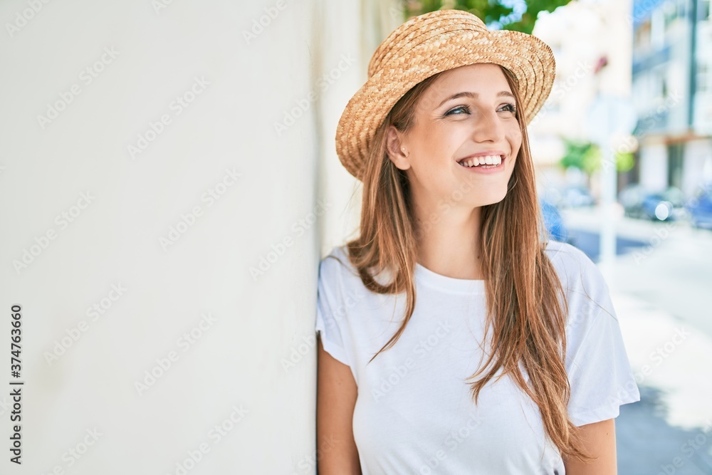 Young blonde woman on vacation smiling happy leaning on the wall at street of city