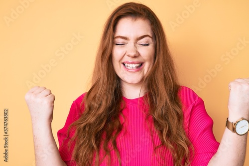 Young redhead woman wearing casual clothes celebrating surprised and amazed for success with arms raised and eyes closed