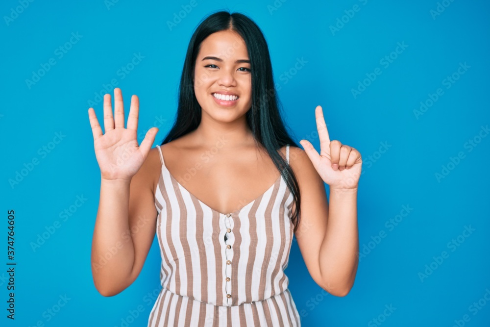 Young beautiful asian girl wearing casual clothes showing and pointing up with fingers number seven while smiling confident and happy. Young beautiful asian girl wearing casual clothes showing and pointing up with fingers number seven while smiling confident and happy.