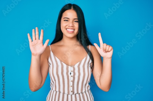 Young beautiful asian girl wearing casual clothes showing and pointing up with fingers number seven while smiling confident and happy.