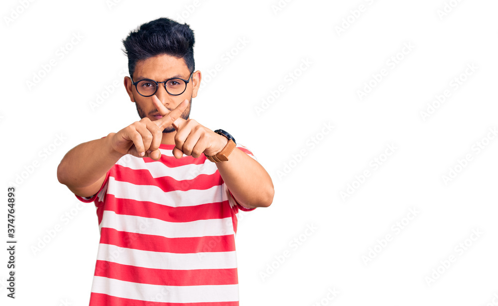 Handsome latin american young man wearing casual clothes and glasses rejection expression crossing fingers doing negative sign Handsome latin american young man wearing casual clothes and glasses rejection expression crossing fingers doing negative sign