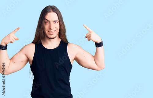 Fotografia Young adult man with long hair wearing rocker style with black clothes and contact lenses looking confident with smile on face, pointing oneself with fingers proud and happy