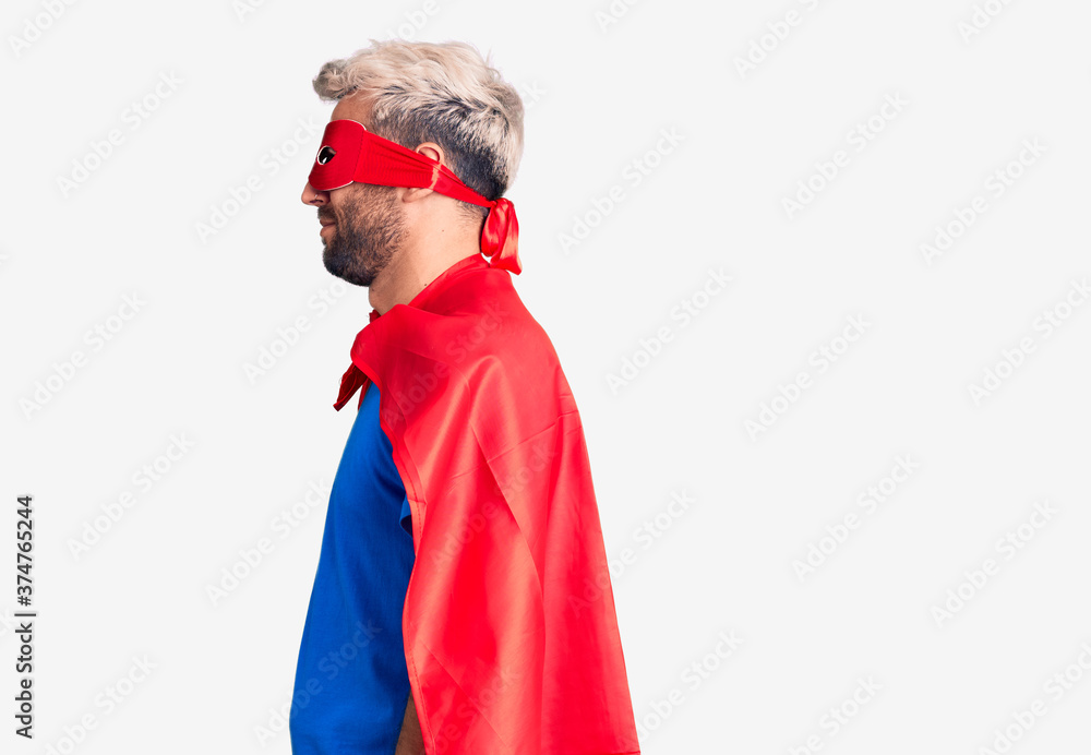 Young blond man wearing super hero custome looking to side, relax profile pose with natural face with confident smile.