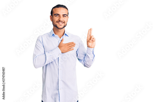 Young handsome man wearing business clothes smiling swearing with hand on chest and fingers up, making a loyalty promise oath © Krakenimages.com