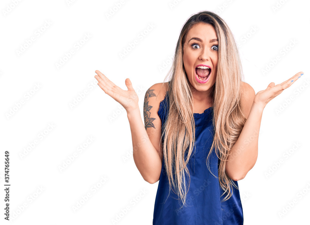 Young beautiful blonde woman wearing casual sleeveless t-shirt celebrating victory with happy smile and winner expression with raised hands Young beautiful blonde woman wearing casual sleeveless t-shirt celebrating victory with happy smile and winner expression with raised hands