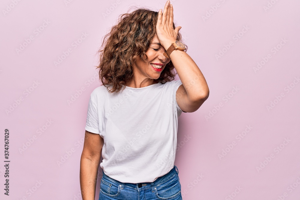 © Krakenimages.com - Middle age beautiful woman wearing casual t-shirt standing over isolated pink background surprised with hand on head for mistake, remember error. Forgot, bad memory concept.