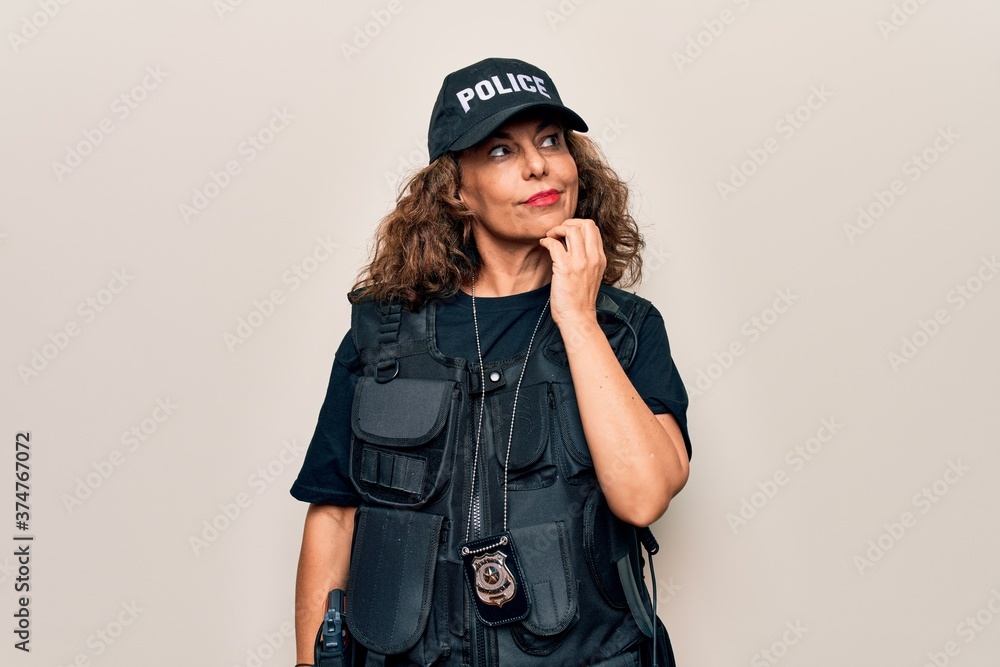 Middle age beautiful policewoman wearing bulletproof uniform and cap over white background thinking concentrated about doubt with finger on chin and looking up wondering Middle age beautiful policewoman wearing bulletproof uniform and cap over white background thinking concentrated about doubt with finger on chin and looking up wondering