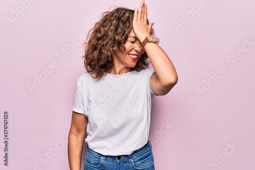 Εκτύπωση καμβά Middle age beautiful woman wearing casual t-shirt standing over isolated pink background surprised with hand on head for mistake, remember error